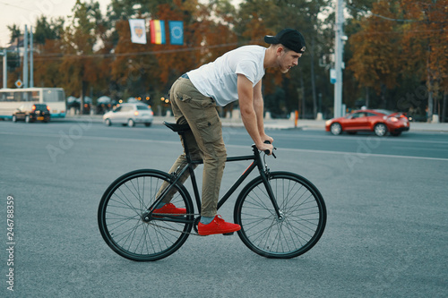Fototapeta Naklejka Na Ścianę i Meble -  Young modern man cycling on a classic bike on the city road