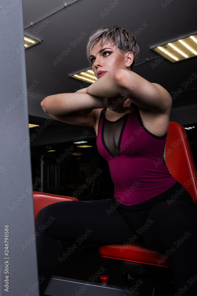 Beautiful sport girl is engaged on a simulator in the gym. Pretty girl with the beautiful tightened figure. Fitness girl in the gym