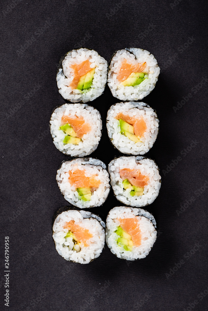 Sushi rolls set served on black stone slate on dark background Sushi rolls set served on black stone slate on dark background