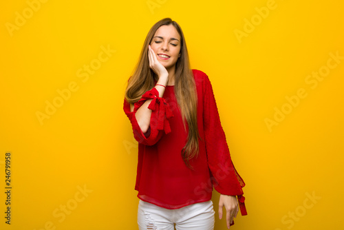 Young girl with red dress over yellow wall with toothache