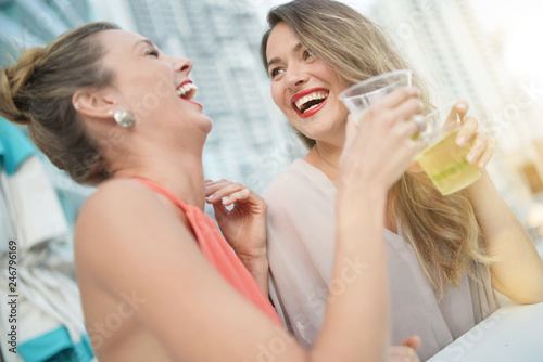 Two attractive funloving friends partying with drinks on rooftop bar in city
