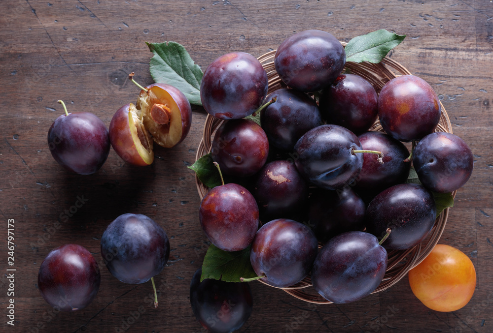 Fototapeta premium Ripe juicy plums on a wooden background.