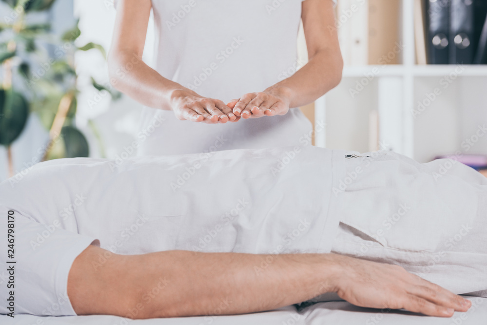 Obraz premium cropped shot of man lying on massage table and receiving reiki treatment