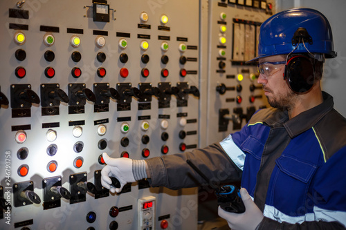 electromechanic in electrical safety gloves holds power cable, cabling connection of high voltage power electric line in industrial distribution fuseboard photo