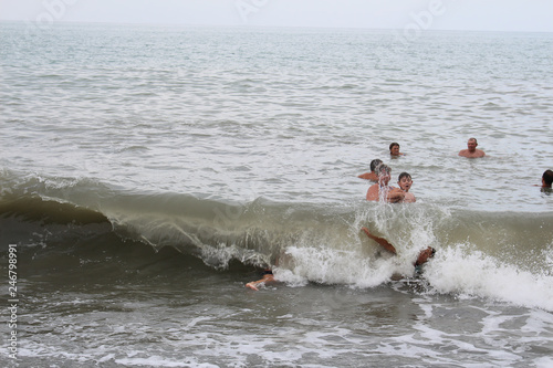 A group of people, family swimming in the sea. Big waves and sea foam.