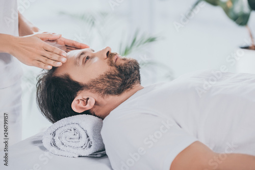 calm bearded man receiving reiki treatment and looking up