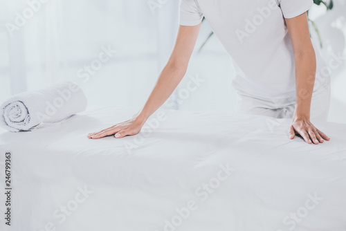 cropped shot of medical worker leaning at white massage table with rolled towel