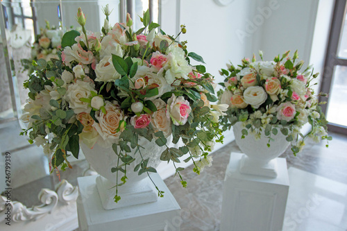 Two beautiful ceramic vases full of faux flowers at white room photo