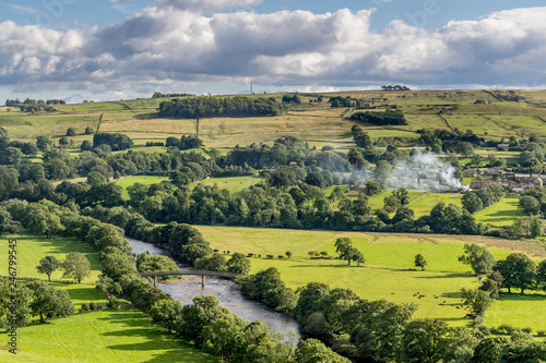 a valley with storm clouds and sheep in the fields. 