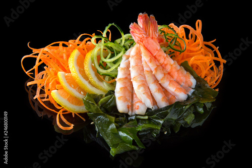 Delicious Ebi Sashimi (Sweet Shrimp, Prawns) with carrot, cucumber, nori, lemon on black background. Traditional Japanese cuisine