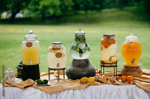 Fresh drink in jars made of lemons, lime and oranges on white festive table. Tasty drink. Lemonade or compote. Drinking concept