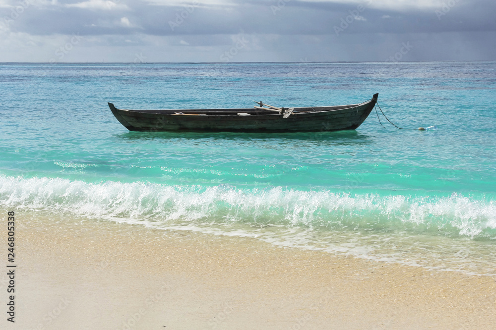 Lazy days on Maldives. Old wooden boat on the water surface near sand beach. Perfect turquoise sea.
