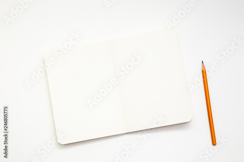 Notebook and pencil on white background. Workplace of the artist or writer. Kraft paper, top view. close-up, mockup.