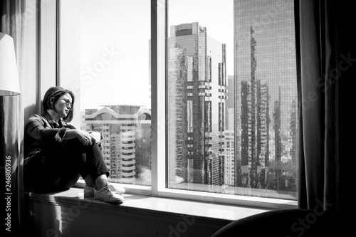 Adult woman sitting by window in skyscaper.