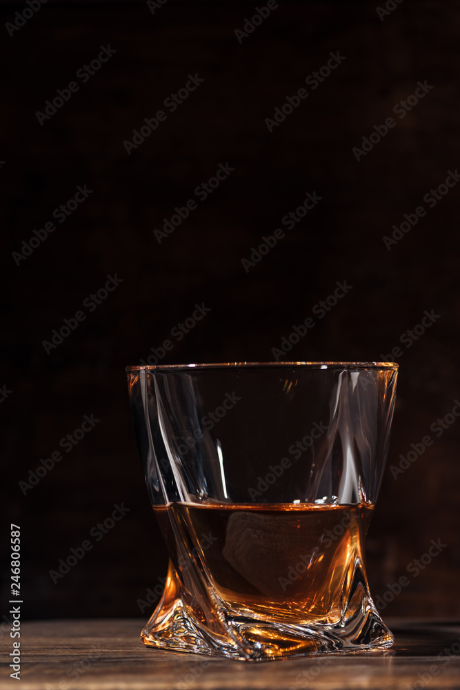 close-up view of whiskey in glass on wooden table on black close-up view of whiskey in glass on wooden table on black
