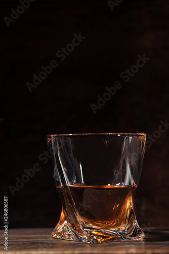 close-up view of whiskey in glass on wooden table on black