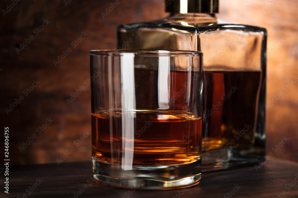 close-up view of glass of whiskey and bottle on wooden table close-up view of glass of whiskey and bottle on wooden table