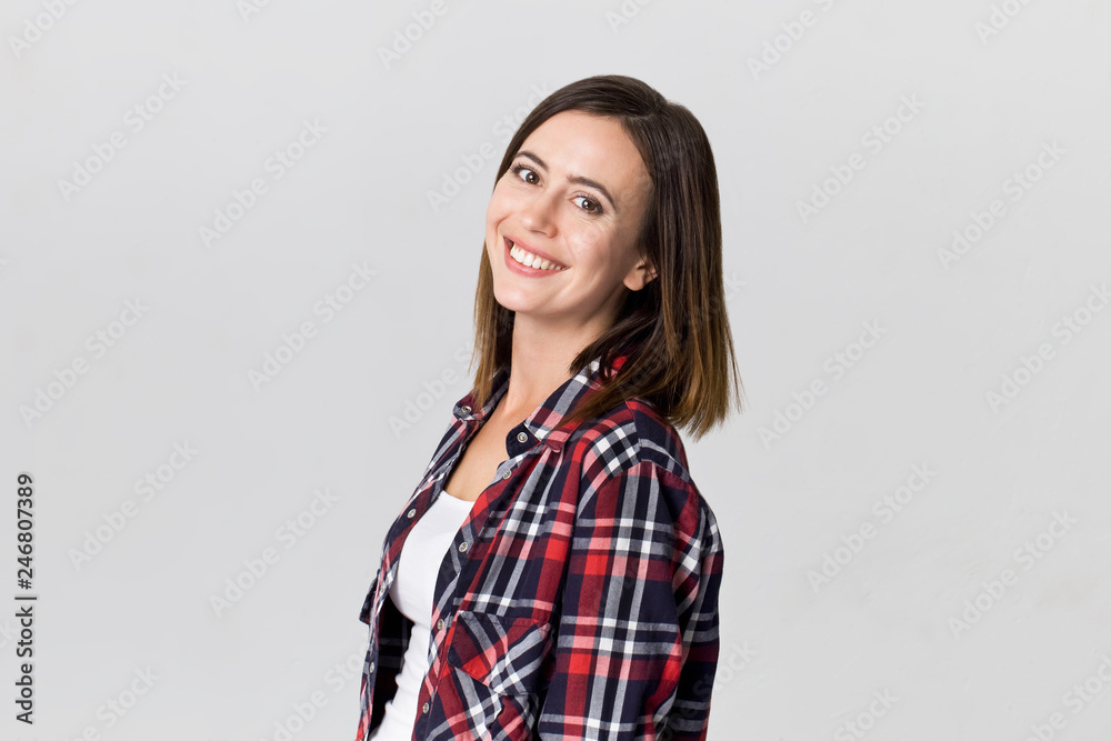 Happy young brunette woman wearing checkered shirt smiling portrait against white background