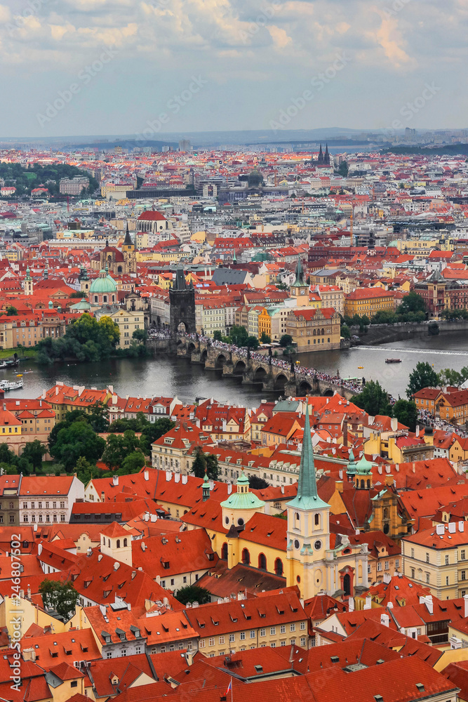 The panoramic view of Prague from the observation desk of Cathedral churh of St. Vitus, Czech Republic. Red roofs, churches, the Charles Bridge and the Vltava river. Cloudy rainy day. 