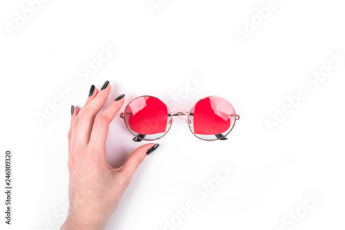 Woman hand taking the round sunglasses with hearts shape on the white background.