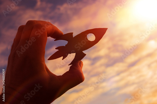rocket in the hand of a man on the background of the evening sky. the aspiration of upward growth.