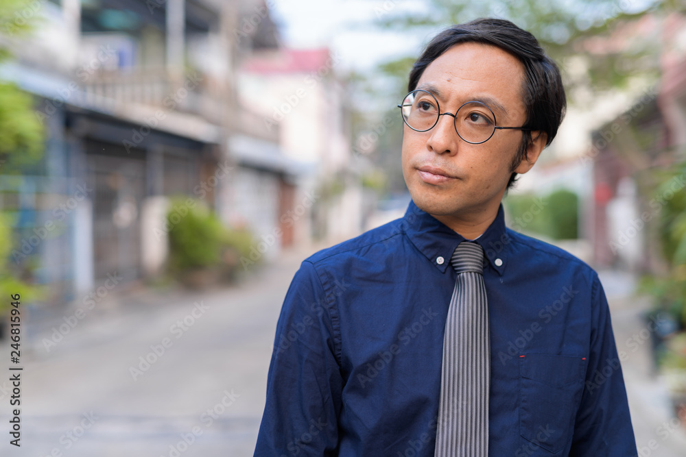 Obraz premium Face of Japanese businessman with eyeglasses thinking outdoors