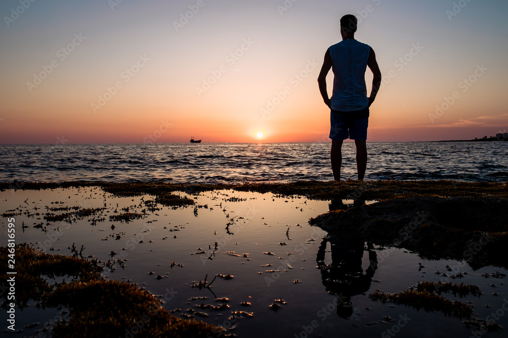 Fototapeta premium man looks at the sunset at the sea