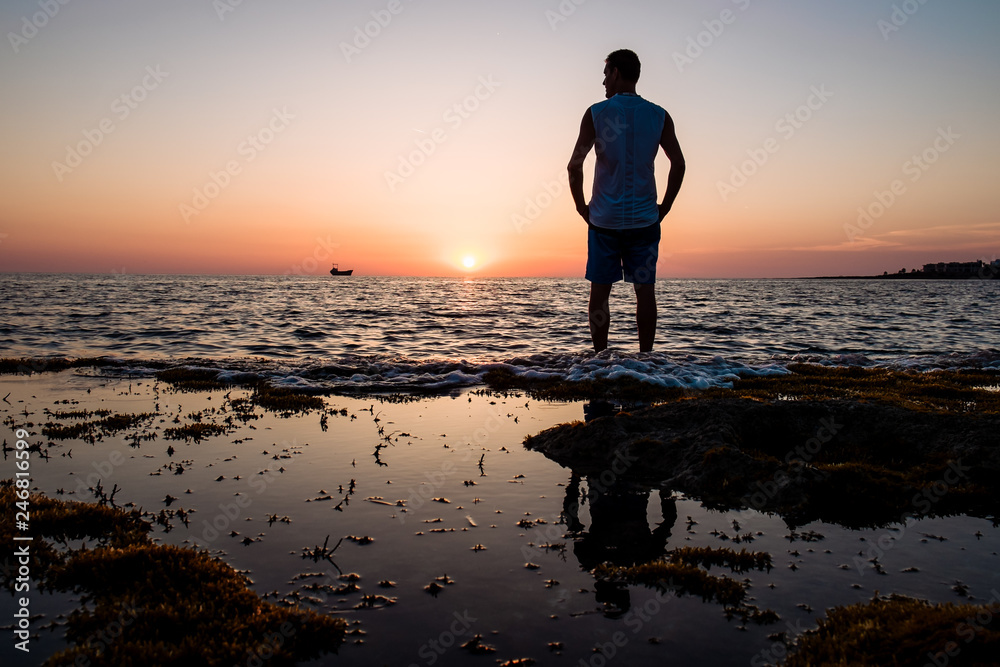man looks at the sunset at the sea