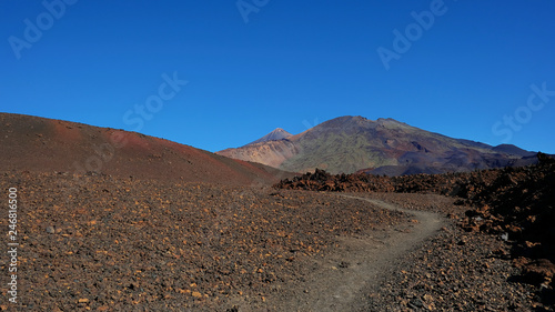 Path through the lunar landscape of Montaña Samara in Teide National Park, one of the most alien-like, volcanic land in Tenerife with views towards Pico del Teide, Pico Viejo, and Las Cuevas Negras