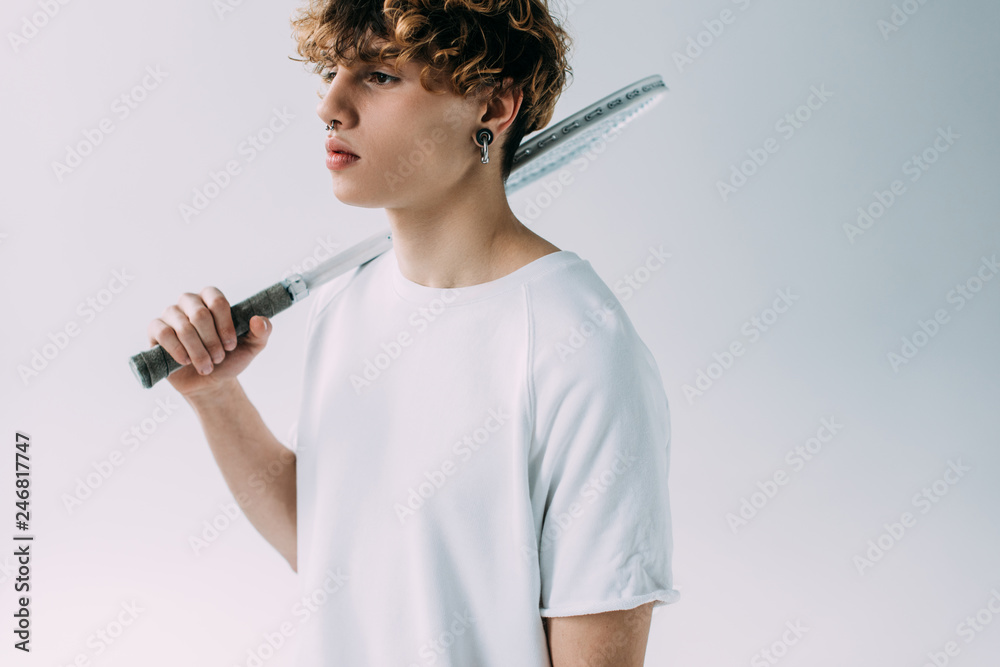 handsome man with curly hair holding tennis racket isolated on grey handsome man with curly hair holding tennis racket isolated on grey