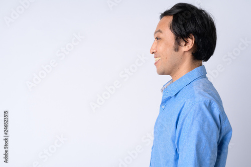 Profile view of happy Japanese businessman smiling against white background