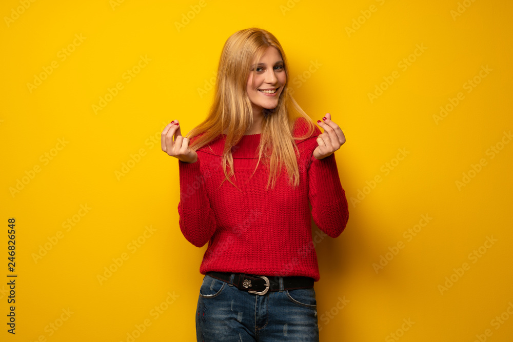 Blonde woman over yellow wall keeping a conversation with the mobile phone Blonde woman over yellow wall keeping a conversation with the mobile phone