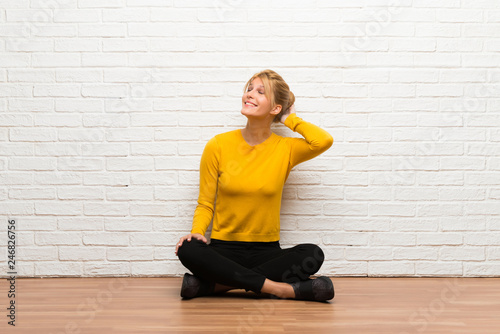 Young girl sitting on the floor thinking an idea while scratching head