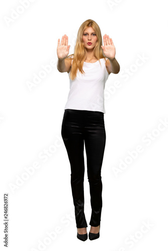 Young blonde woman making stop gesture for disappointed with an opinion over isolated white background
