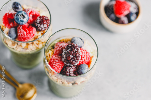 Top view on chia pudding with matcha tea, organic granola, frozen berries in glasses. The concept of healthy vegan food.