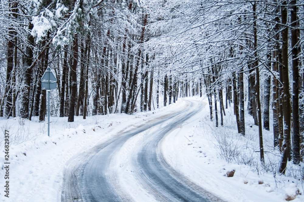 Slippery icy road through the forest with trees and snow on both sides Slippery icy road through the forest with trees and snow on both sides