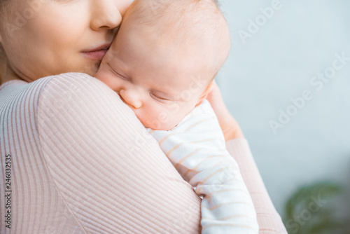 cropped shot of young mother carrying adorable sleeping baby