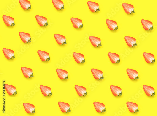 Diagonal pattern from ripe juicy strawberries cut in half on bright yellow background. Creative minimalist flat lay. Vitamins vegan healthy diet concept. Poster wallpaper template