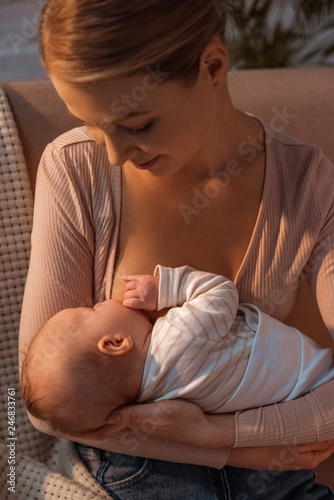 beautiful smiling young mother breastfeeding baby at night