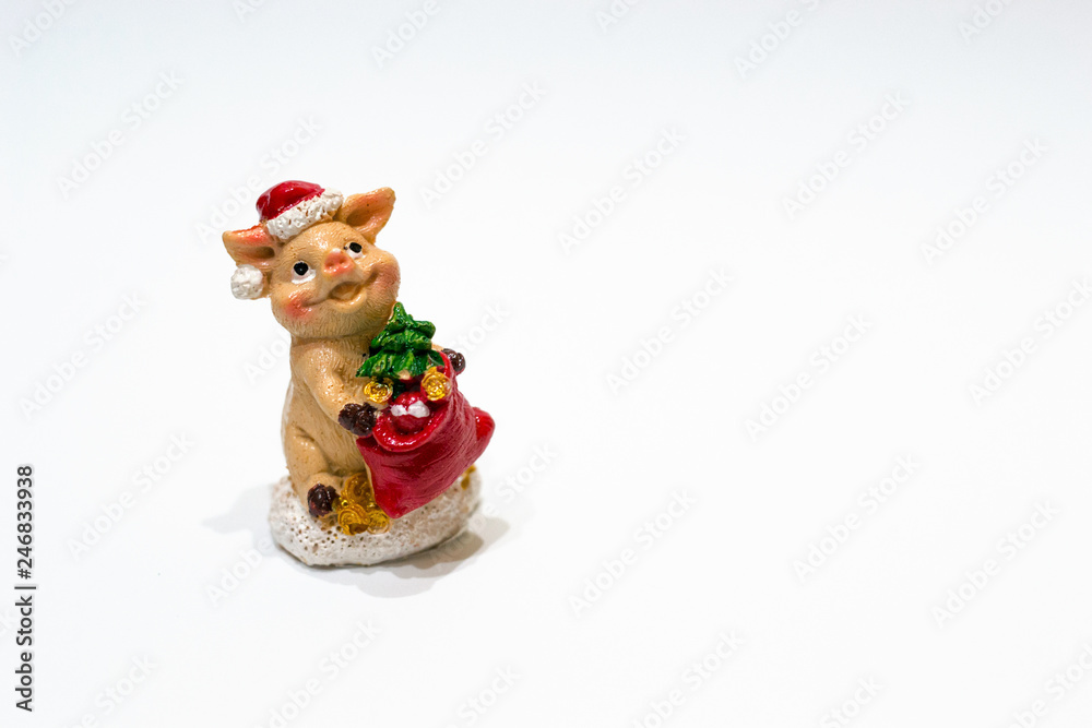 Concept of winter holidays, copy space. Christmas toy ceramic figurine pig with fir tree and hat as a symbol of Chine new 2019 year isolated on white background.