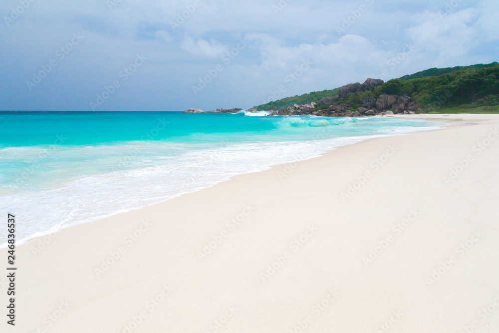 The beach on the Seychelles with white sand turquoise water and blue sky