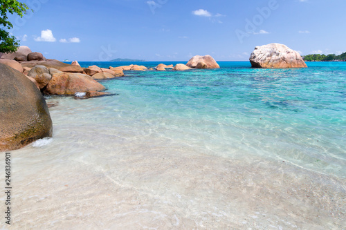 Beach with blue water and blue sky and some rocks