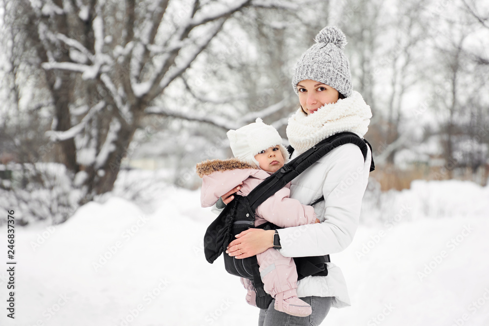 Little baby girl and her mother walking outside in winter Mother is