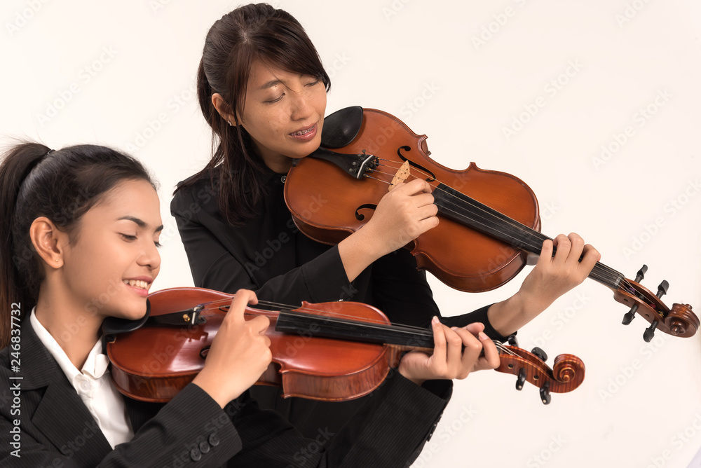 In violin practice class,two beautiful woman hold wooden violin.teach and practice playing violin together to prepare for the concert. In violin practice class,two beautiful woman hold wooden violin.teach and practice playing violin together to prepare for the concert.
