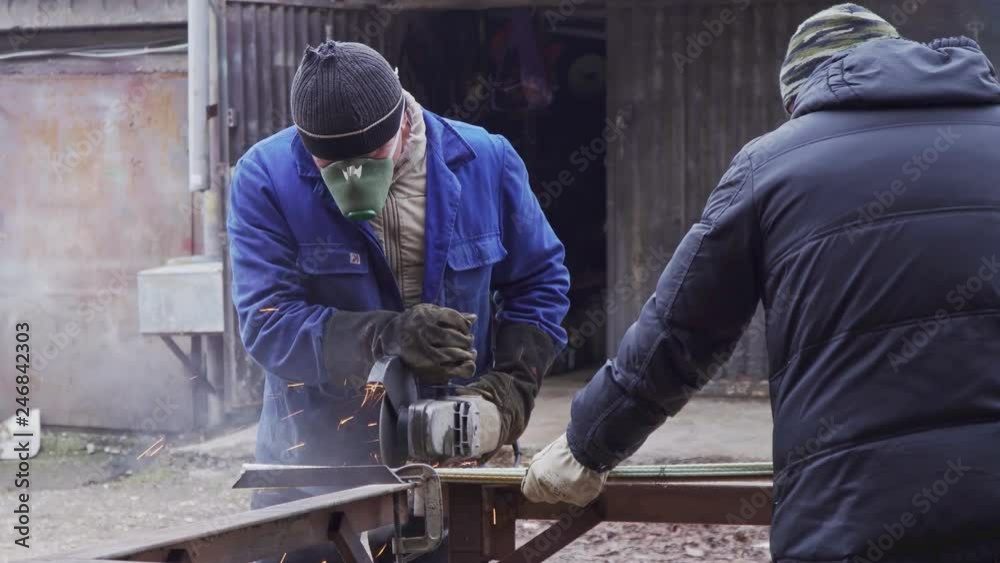 Two workers working with a grinder with a metal structure closeup Two workers working with a grinder with a metal structure closeup
