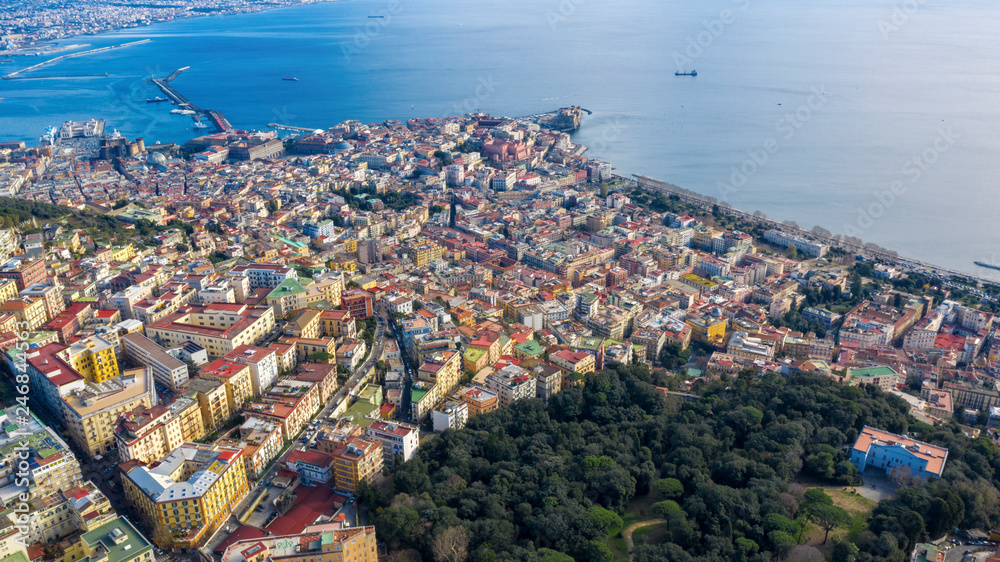 Aerial view of Naples from the Vomero district. You can see Castel Sant'elmo in the foreground while in the background the city's port, the Vesuvius and the Ovo castle. There are houses and buildings.
