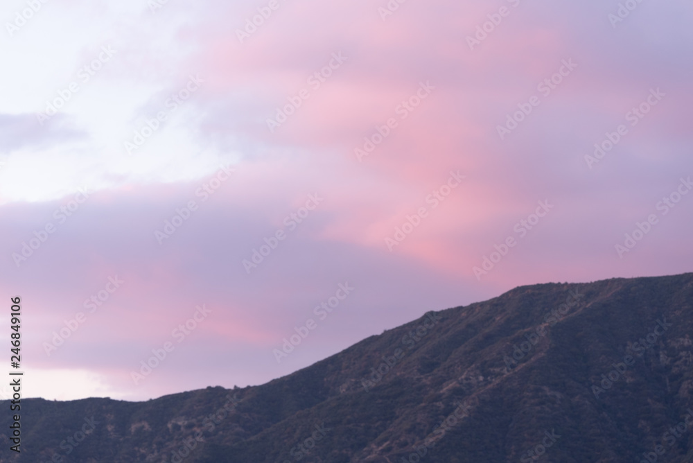 Pink and blue clouds over mountains.