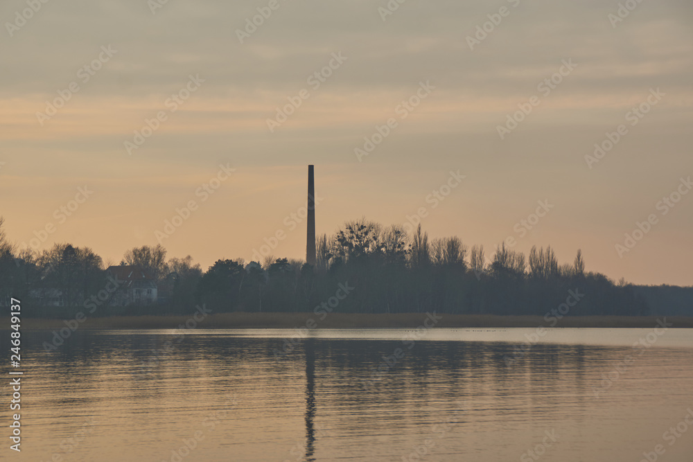 smoke stack with reflection at sunset