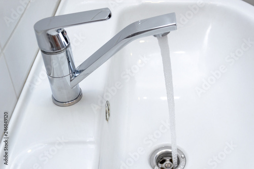 Dripping water from the single handle mixer tap mounted on a wash basin