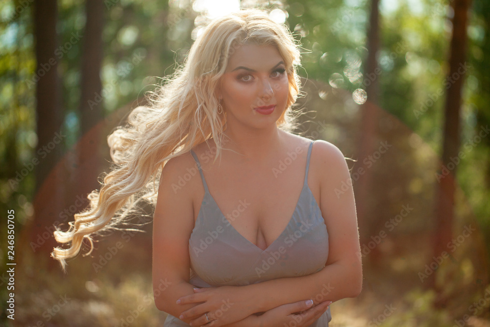 Young beautiful blonde woman in blue sexy dress - neglegee pegnoir underwear posing in forest in summer Young beautiful blonde woman in blue sexy dress - neglegee pegnoir underwear posing in forest in summer